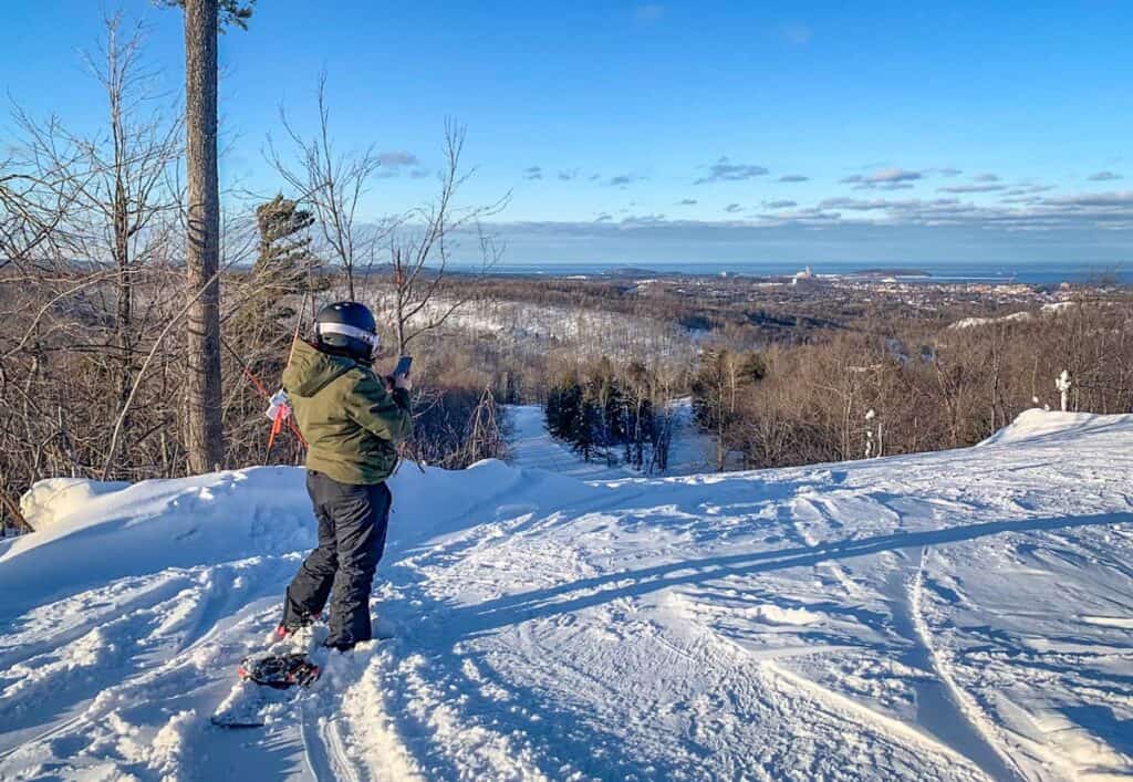 marquette mountain summit snowboarder taking photo of lake superior views
